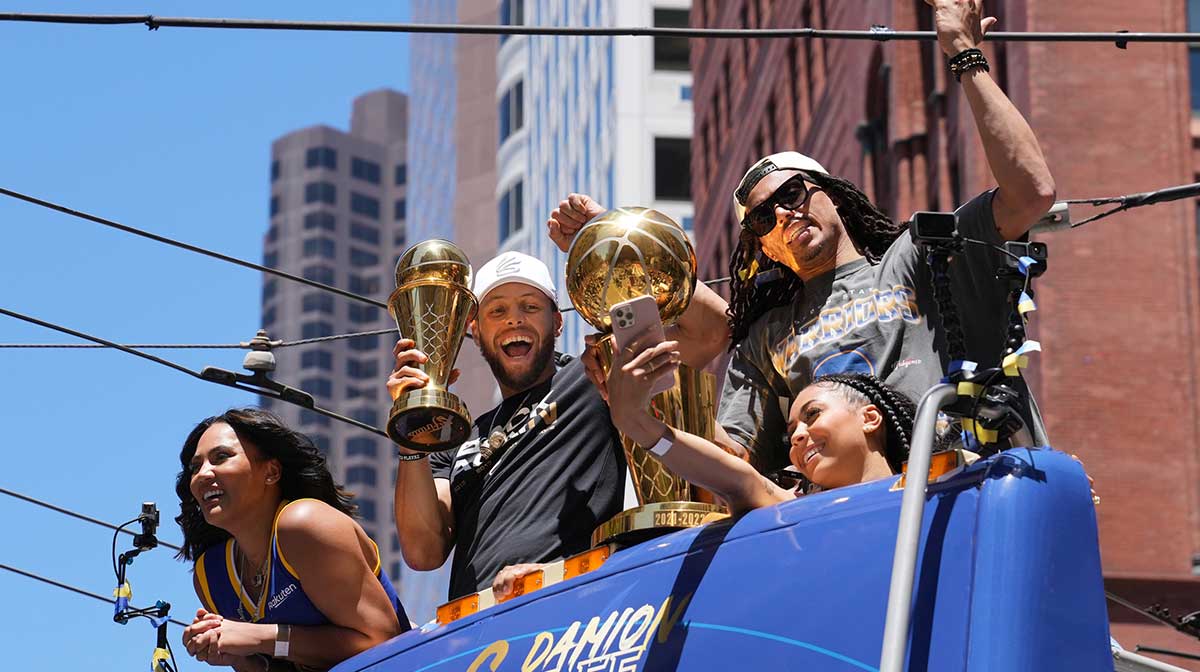 Golden State Warriors guard Stephen Curry (middle) holds his MVP trophy as guard Damion Lee (right) holds the championship trophy during the Golden State Warriors championship parade in downtown San Francisco.