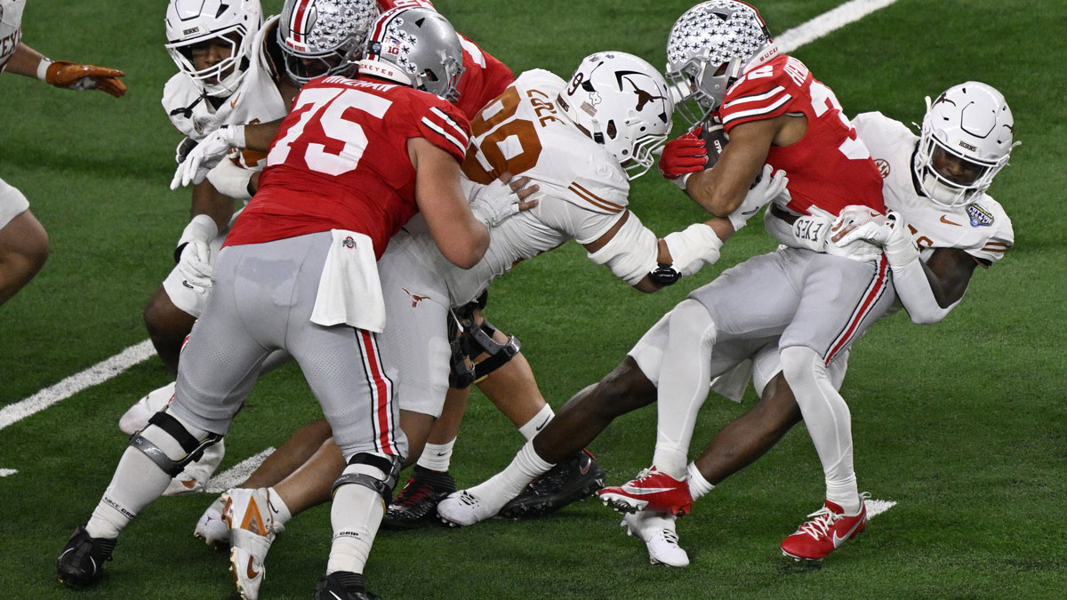 Ohio State Buckeyes running back TreVeyon Henderson (32) is tackled by Texas Longhorns linebacker Colin Simmons (11) and defensive lineman Jermayne Lole (99) during the second quarter of the College Football Playoff semifinal in the Cotton Bowl at AT&T Stadium.