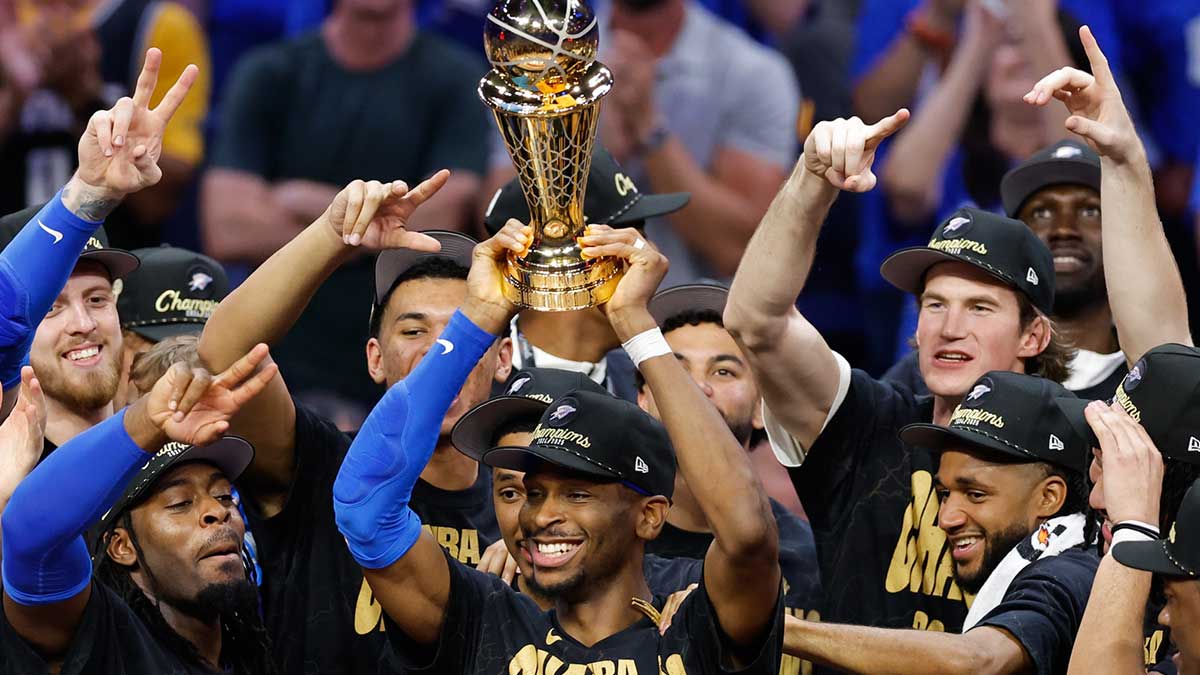 Thunder guard Shai Gilgeous-Alexander (2) lifts the Larry O'Brien Championship Trophy as the Oklahoma City Thunder celebrate after winning game seven of the 2025 NBA Finals against the Indiana Pacers at Paycom Center with Kobe Bryant and Lou Williams in the background