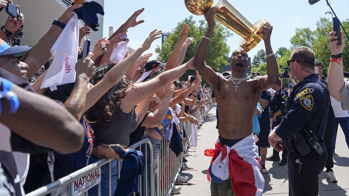 Oklahoma City Thunder guard Shai Gilgeous-Alexander carries the Larry O'Brien trophy as he celebrates with fans.