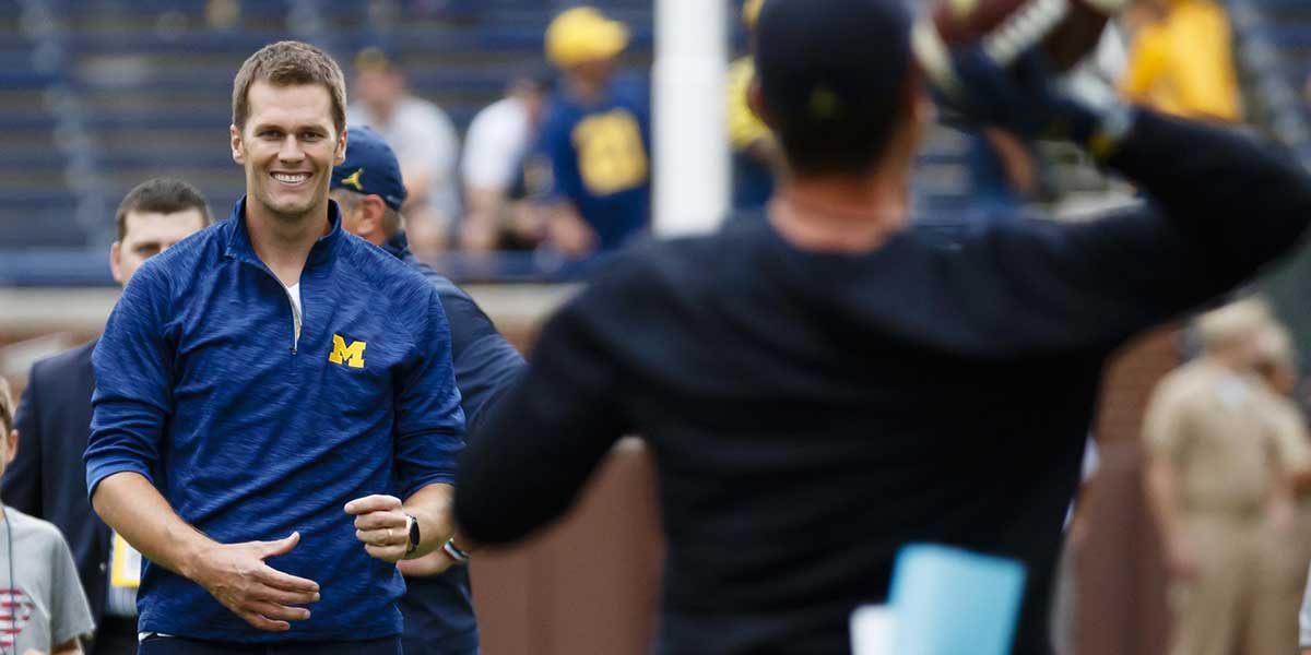 New England Patriots quarterback Tom Brady and Michigan Wolverines head coach Jim Harbaugh pass the ball around during warm ups prior to the game against the Colorado Buffaloes at Michigan Stadium.