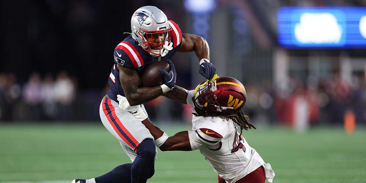 Washington Commanders saftey Tyler Owens (40) tries to tackle New England Patriots running back TreVeyon Henderson (32) during the first half at Gillette Stadium.
