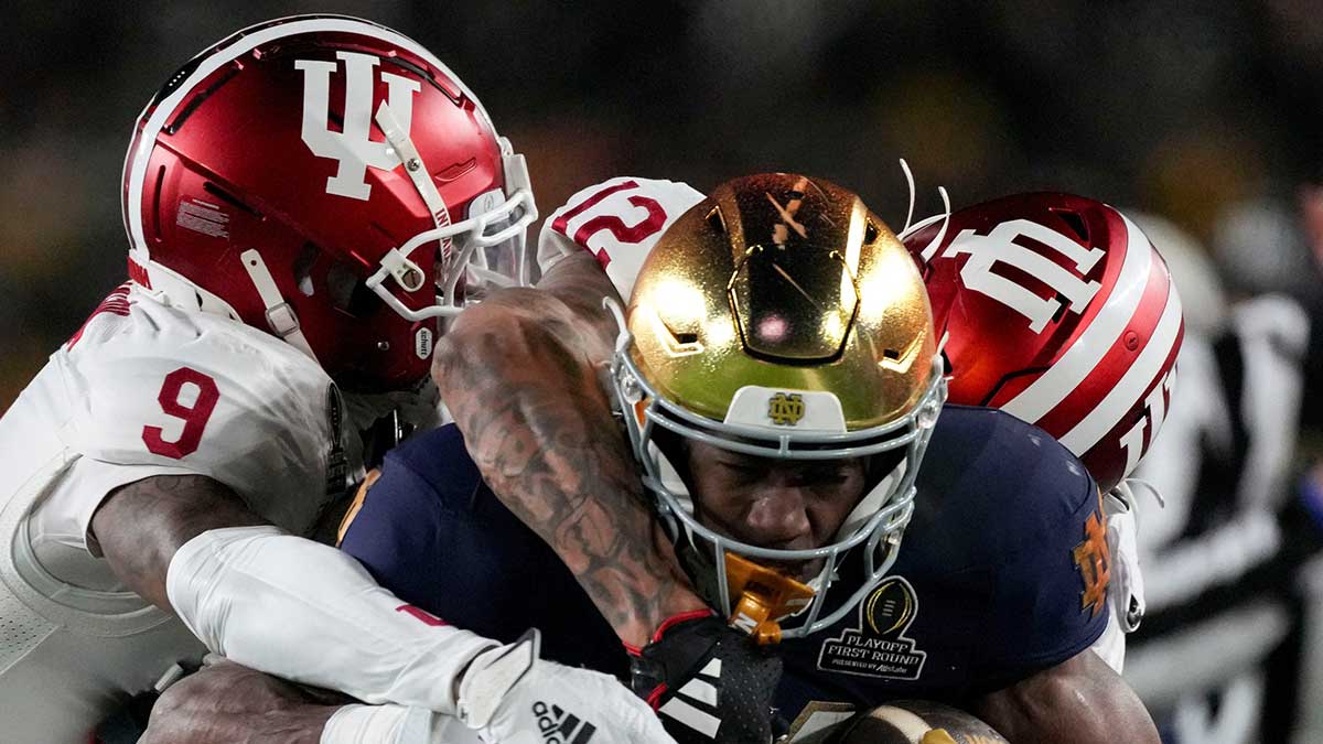 Indiana Hoosiers defensive back Jamier Johnson (9) and defensive back Terry Jones Jr. (12) tackle Notre Dame Fighting Irish running back Jadarian Price (24) during the first half of a game between the Indiana Hoosiers and the Notre Dame Fighting Irish in first round of the College Football Playoff on Friday, Dec. 20, 2024, in South Bend.