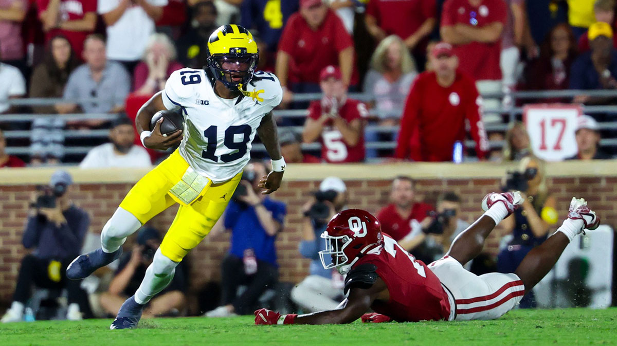 Michigan Wolverines quarterback Bryce Underwood (19) runs past Oklahoma Sooners linebacker Sammy Omosigho (7) during the second half at Gaylord Family-Oklahoma Memorial Stadium.