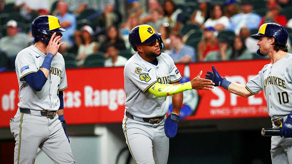 Milwaukee Brewers designated hitter Christian Yelich (22) celebrates with Milwaukee Brewers center fielder Jackson Chourio (11) and Milwaukee Brewers right fielder Sal Frelick (10) after scoring during the fifth inning against the Texas Rangers at Globe Life Field.