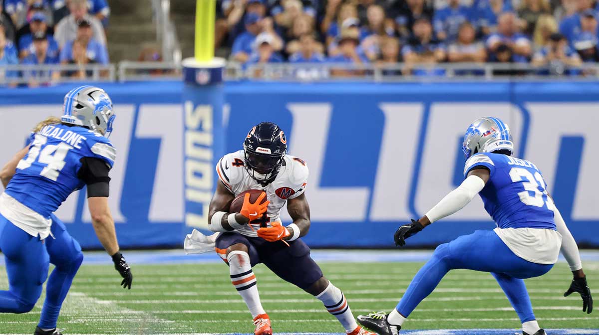 Chicago Bears running back D'Andre Swift (4) carries the ball defended by Detroit Lions linebacker Alex Anzalone (34) and safety Kerby Joseph (31) during the second quarter of the game at Ford Field.