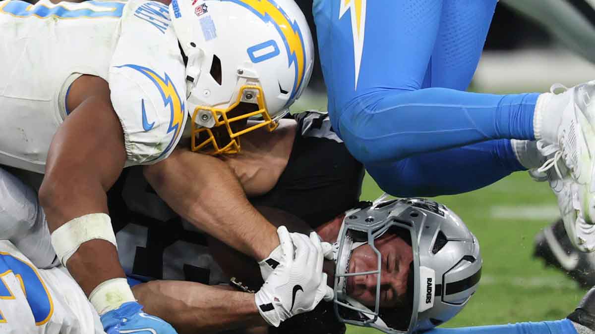 Las Vegas Raiders tight end Brock Bowers (89) is tackled by Los Angeles Chargers linebacker Daiyan Henley (0) during the fourth quarter at Allegiant Stadium.