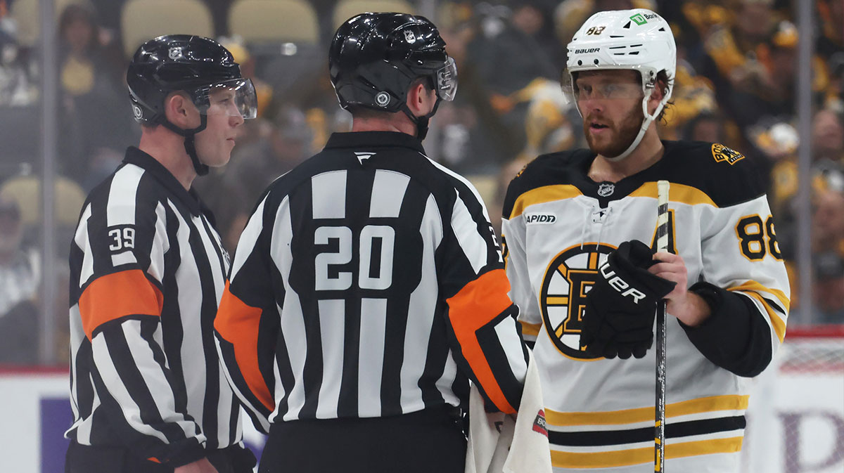 NHL referees Brandon Blandina (63) and Mitch Dunning (20) talk with Boston Bruins right wing David Pastrnak (88) against the Pittsburgh Penguins during the third period at PPG Paints Arena.