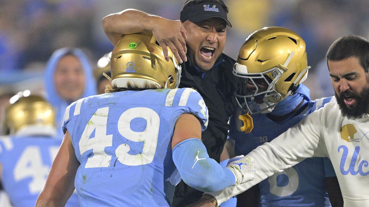 UCLA Bruins defensive coordinator Ikaika Malloe, center, celebrates with linebacker Carson Schwesinger (49) defensive back Jaylin Davies (6) after an interception in the second half against the Iowa Hawkeyes at the Rose Bowl.