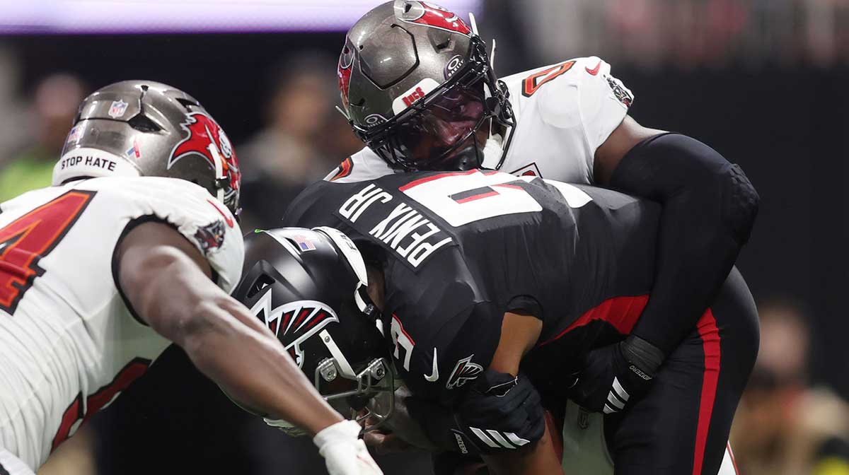 Tampa Bay Buccaneers linebacker Yaya Diaby (0) and defensive tackle Calijah Kancey (94) tackle Atlanta Falcons quarterback Michael Penix Jr. (9) during the second quarter at Mercedes-Benz Stadium.