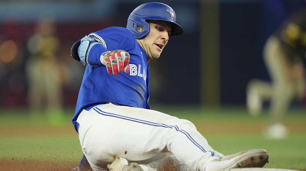 Toronto Blue Jays center fielder Dalton Varsho (5) slides into third base on his RBI triple against the San Diego Padres during the eleventh inning at Rogers Centre.