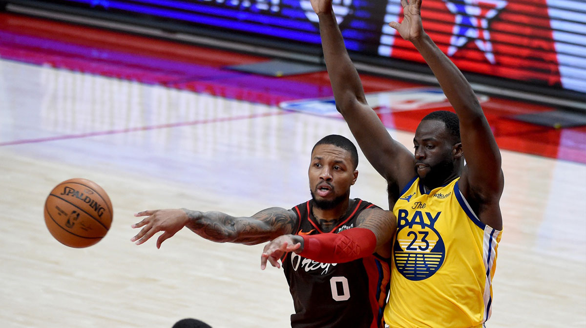 Portland Trail Blazers guard Damian Lillard (0) passes the ball on Golden State Warriors forward Draymond Green (23) during the second half of the game at Moda Center. The Blazers won 108-106.