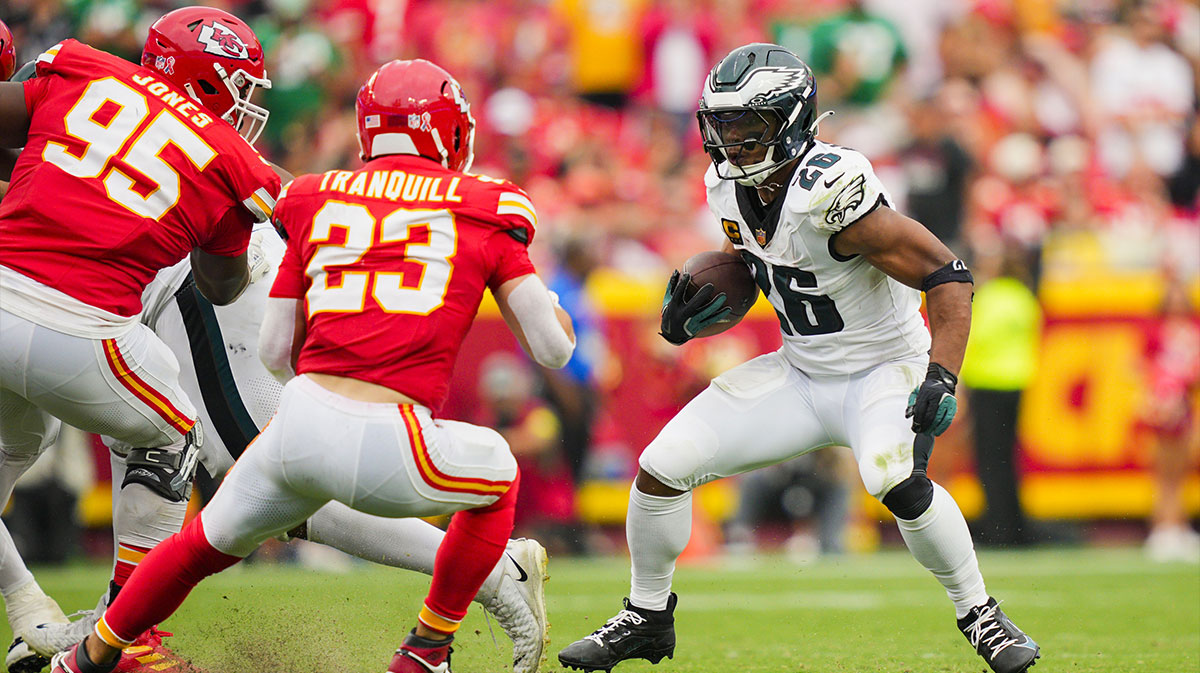Philadelphia Eagles running back Saquon Barkley (26) runs the ball against Kansas City Chiefs defensive tackle Chris Jones (95) and linebacker Drue Tranquill (23) during the second half at GEHA Field at Arrowhead Stadium.