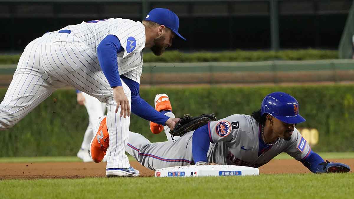New York Mets shortstop Francisco Lindor (12) dives safely into first base as Chicago Cubs first base Michael Busch (29) makes a late tag during the first inning at Wrigley Field.