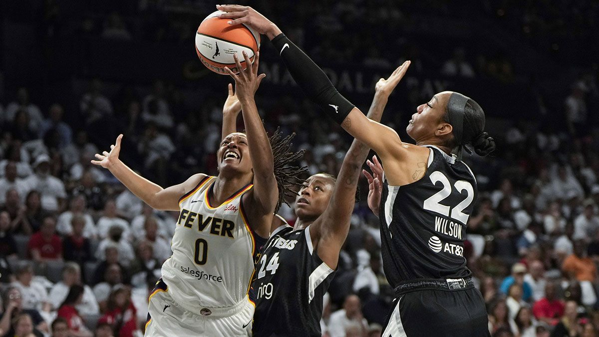 Indiana Fever guard Kelsey Mitchell (0) attempts to score a layup against Las Vegas Aces center A'ja Wilson (22) and guard Jewell Loyd (24) during the second quarter in game one of the second round for the 2025 WNBA Playoffs at Michelob Ultra Arena.