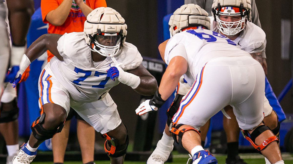 Florida Gators offensive lineman Knijeah Harris (77) explodes from the line against fellow player Florida Gators offensive lineman Riley Simonds (64) during practice at Sanders Practice Fields Tuesday morning, August 8, 2023. Their first game is against the Utah Utes on Thursday August 31, in Salt Lake City, Utah.