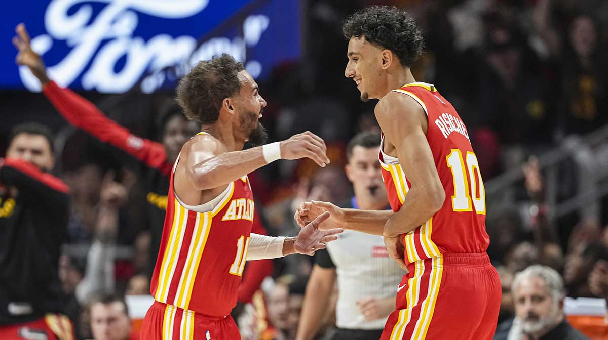 Hawks forward Zaccharie Risacher (10) reacts with guard Trae Young (11) after making a three point basket for his first points in the NBA against the Brooklyn Nets during the first half at State Farm Arena
