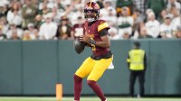 Washington Commanders quarterback Jayden Daniels (5) looks to pass against the Green Bay Packers in the second quarter at Lambeau Field.