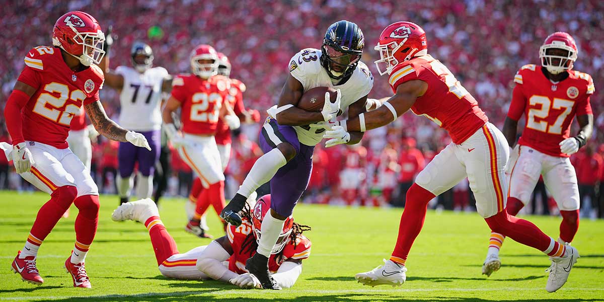 Baltimore Ravens running back Justice Hill (43) evades a tackle from Kansas City Chiefs safety Jaden Hicks (21) to score a touchdown during the first quarter at GEHA Field at Arrowhead Stadium. 