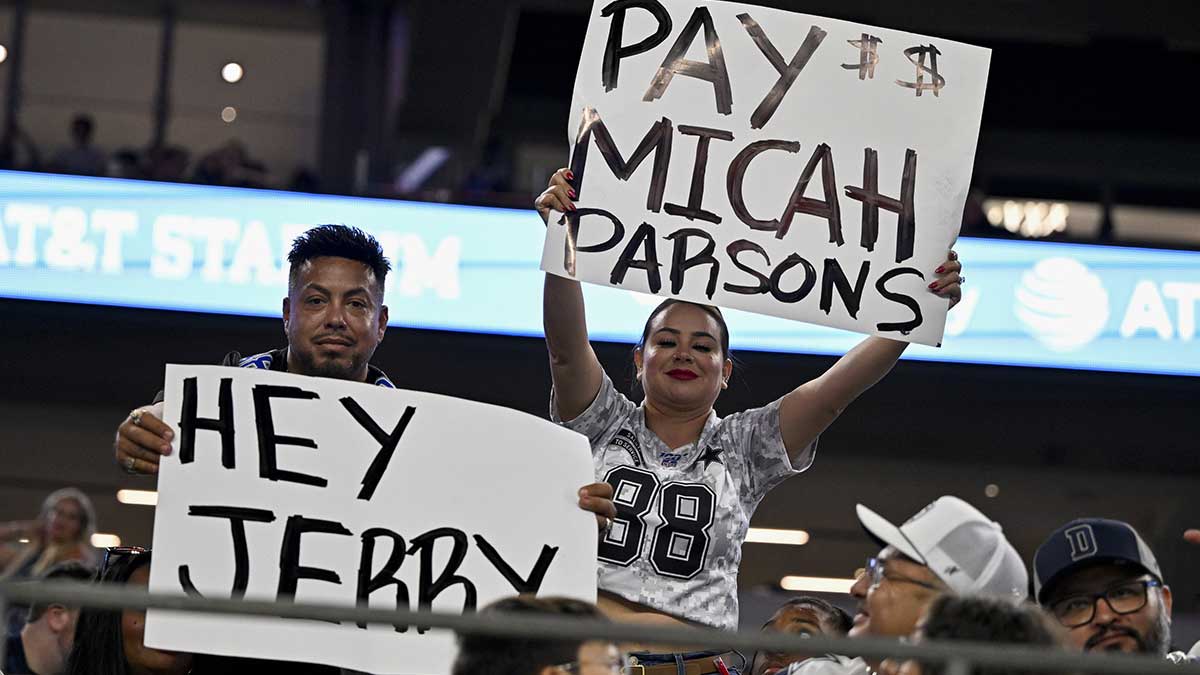 Dallas Cowboys fans hold up signs to owner Jerry Jones and defensive end Micah Parsons (11) during the second half of the game against the Baltimore Ravens at AT&T Stadium.