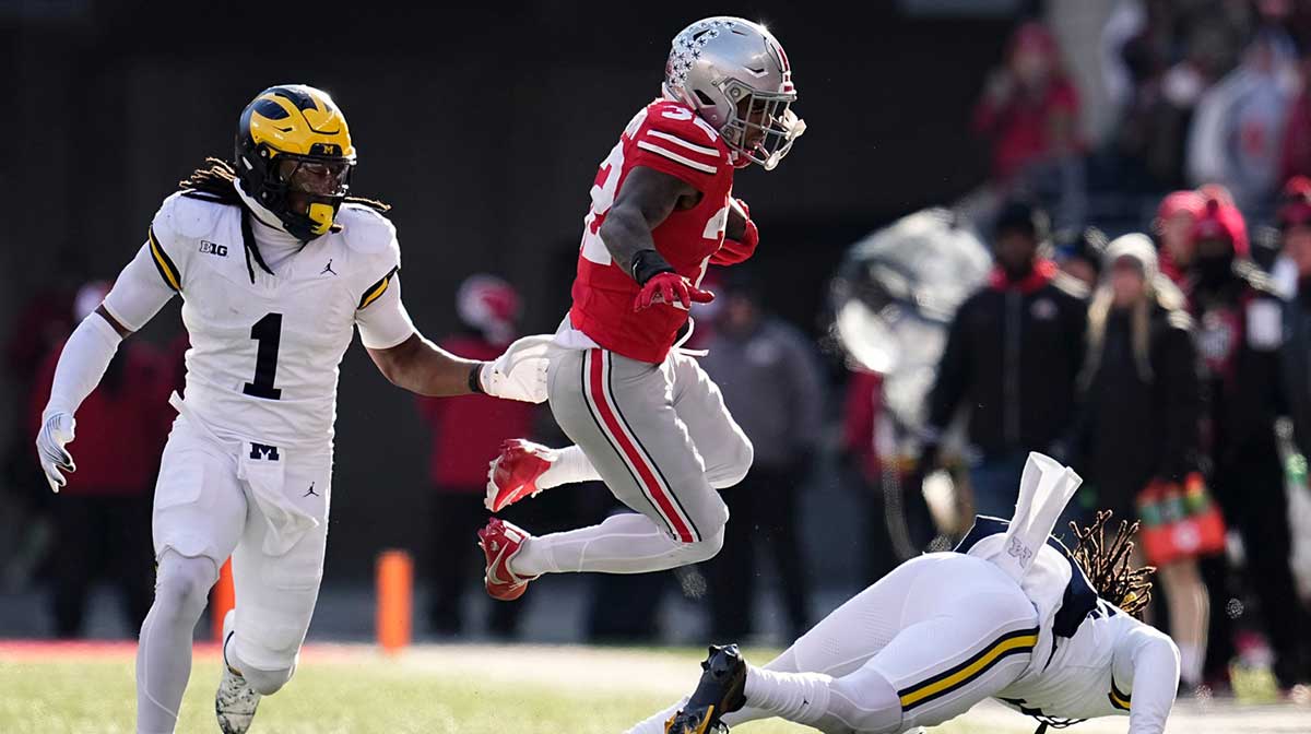 Ohio State Buckeyes running back TreVeyon Henderson (32) leaps in front of Michigan Wolverines linebacker Jaishawn Barham (1) during the second half of the NCAA football game at Ohio Stadium in Columbus on Saturday, Nov. 30, 2024. Michigan won 13-10.