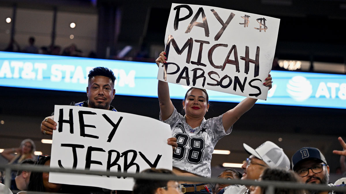 Dallas Cowboys fans hold up signs to owner Jerry Jones and defensive end Micah Parsons (11) during the second half of the game against the Baltimore Ravens at AT&T Stadium.