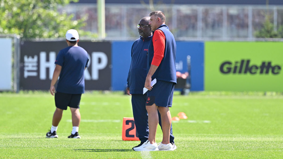 Patriots head coach Mike Vrabel (red sleeves) and defensive coordinator Terrell Williams watch players during training camp at Gillette Stadium