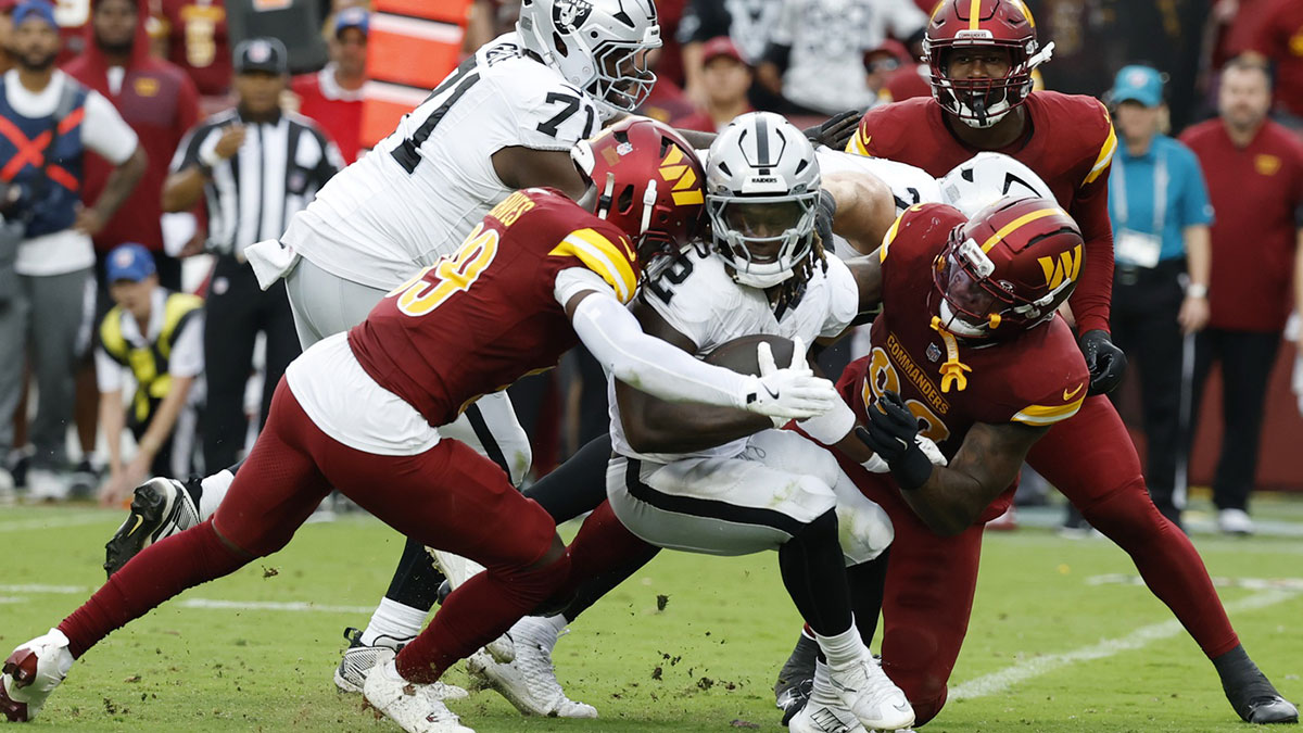 Las Vegas Raiders running back Ashton Jeanty (2) is tackled by Washington Commanders safety Jeremy Reaves (39) and Commanders defensive end Dorance Armstrong (92) during the third quarter at Northwest Stadium.