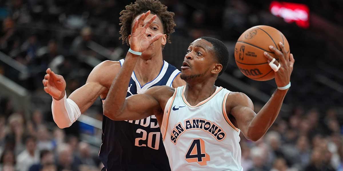 Spurs guard De'Aaron Fox (4) dribbles against Dallas Mavericks forward Caleb Martin (16) in the first half at Frost Bank Center