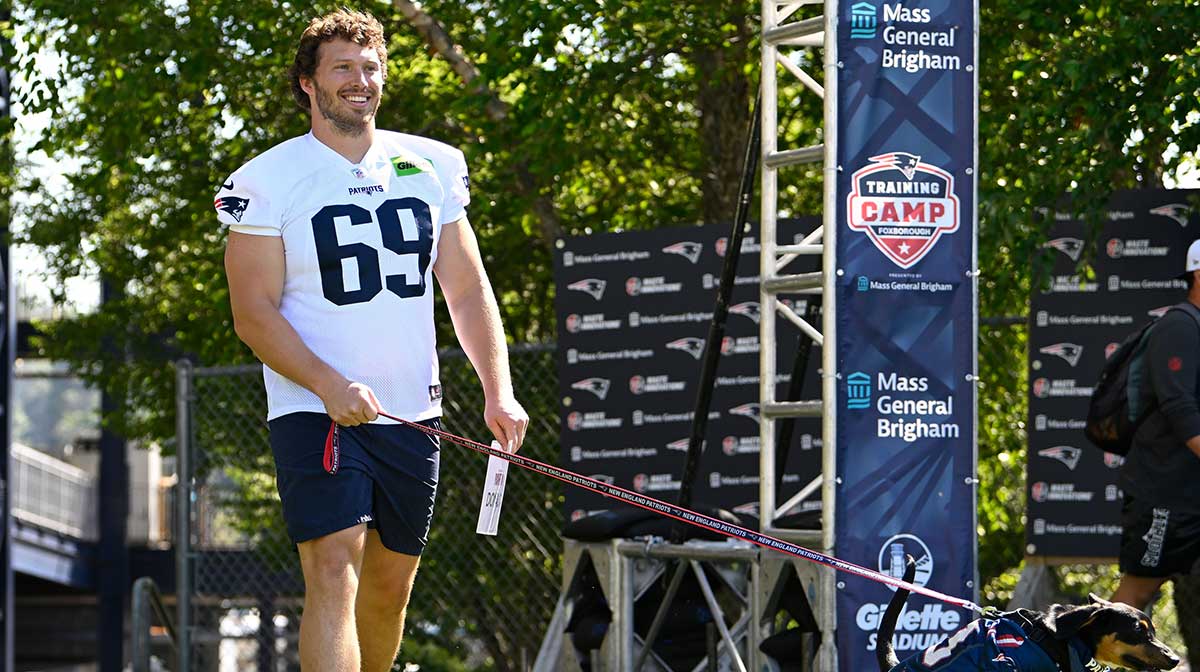 New England Patriots guard Cole Strange (69) delivers a puppy to a local family as part of the Patriots pet adoption event before training camp at Gillette Stadium.