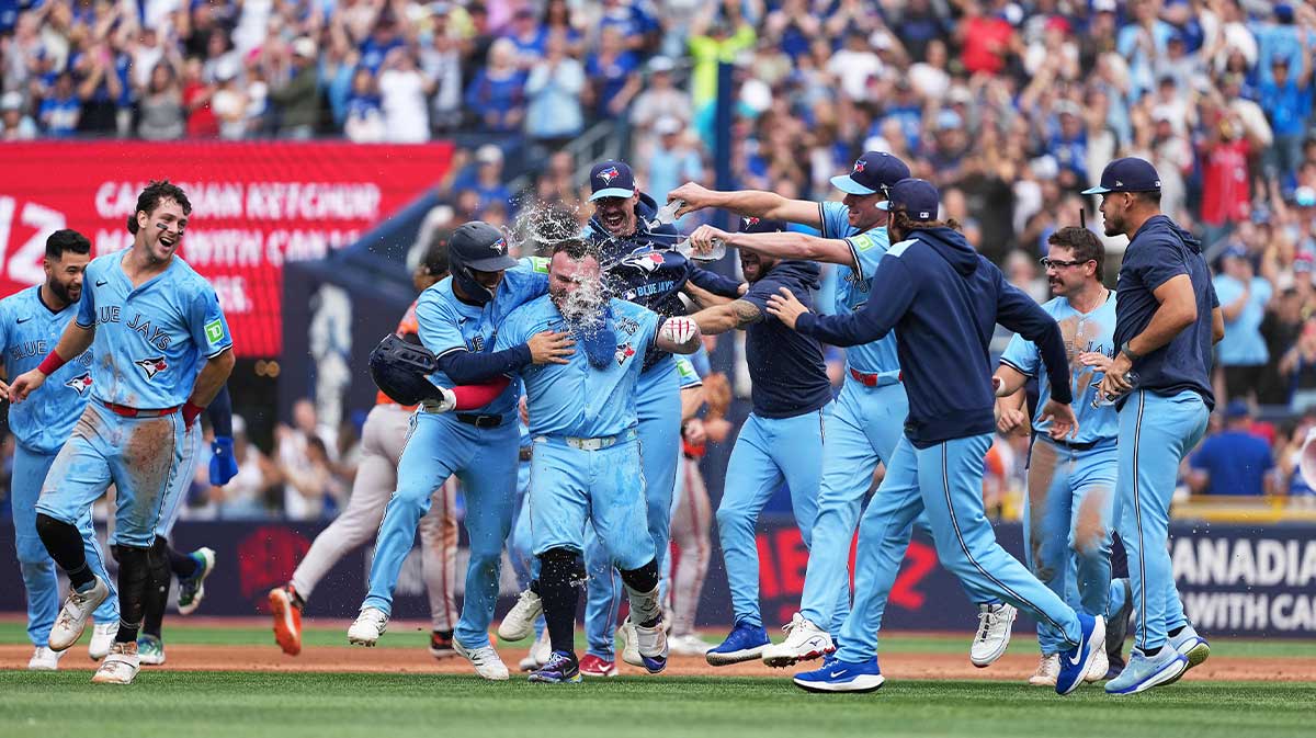 Toronto Blue Jays catcher Alejandro Kirk (30) is swarmed by his teammates after sacrificing in the winning run against the Baltimore Orioles at the end of the ninth inning at Rogers Centre.