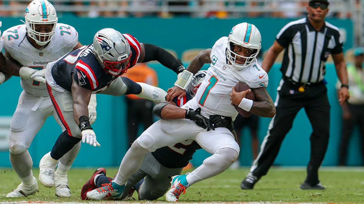 Miami Dolphins quarterback Tua Tagovailoa (1) is tailed by New England Patriots linebacker Harold Landry III (2) in the fourth quarter at Hard Rock Stadium.