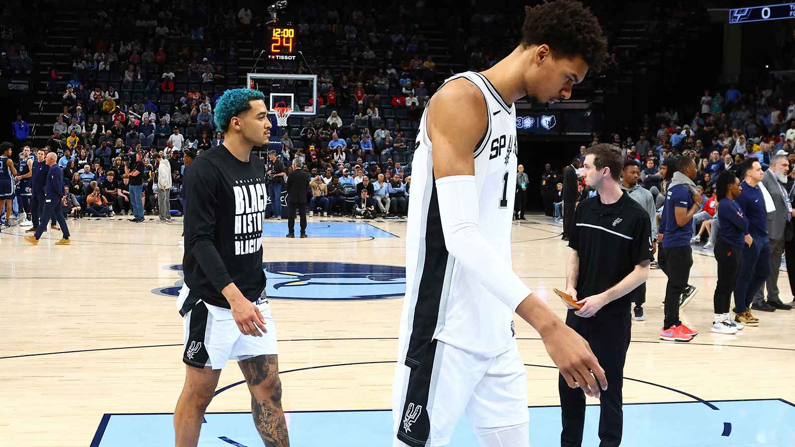 San Antonio Spurs forward Jeremy Sochan (10) and San Antonio Spurs center Victor Wembanyama (1) walk off the court after a delayed start to the game, as medical personnel check on a fan before the game against the Memphis Grizzlies at FedExForum. 
