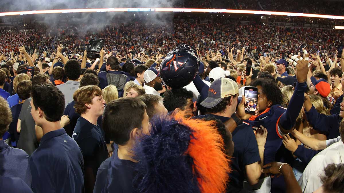 Virginia Cavaliers players and fans celebrate on the field after the Cavaliers' win over the Florida State Seminoles in two overtimes at Scott Stadium.