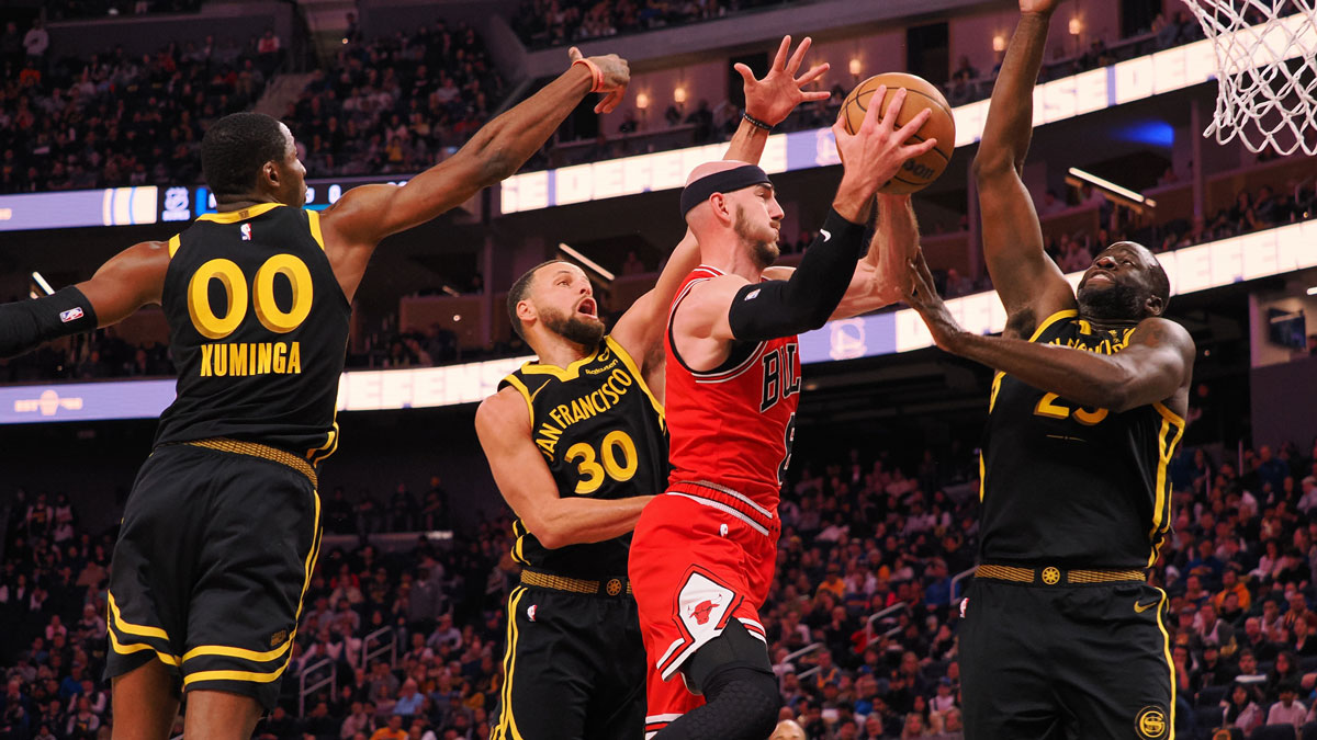 Bulls forward Alex Caruso (6) drives in between Golden State Warriors forward Jonathan Kuminga (00), guard Stephen Curry (30), and forward Draymond Green (23) during the third quarter at Chase Center with Warriors' Joe Lacob in the background