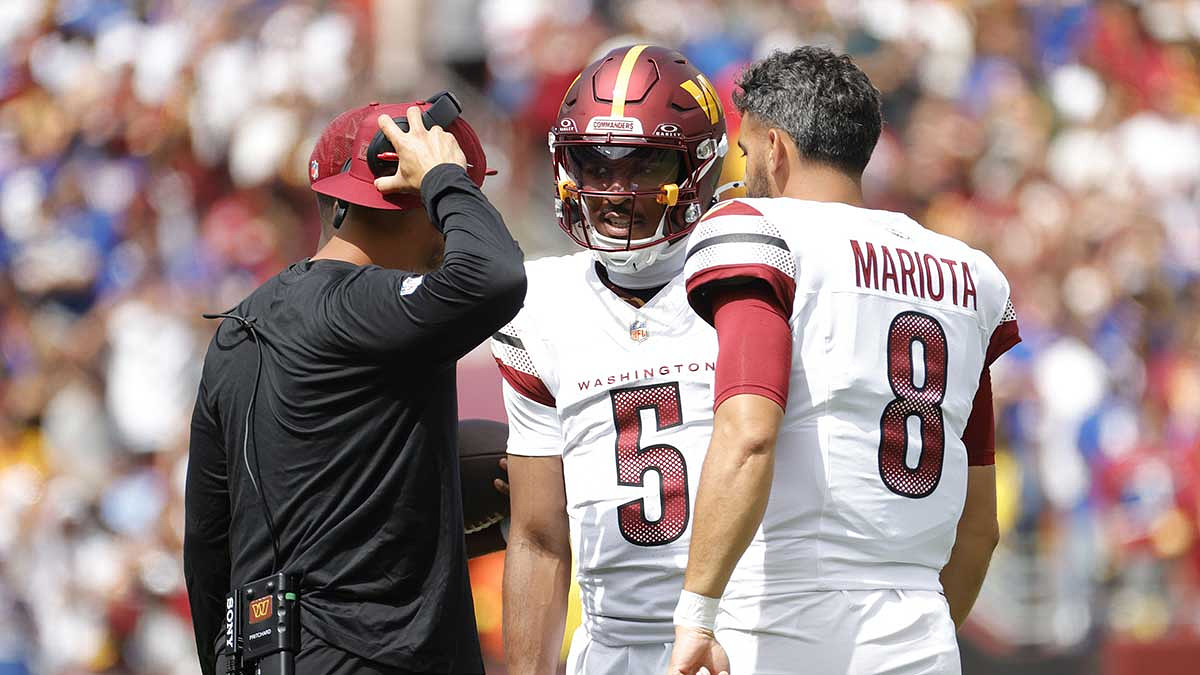 Washington Commanders quarterback Jayden Daniels (5) and Commanders quarterback Marcus Mariota (8) look on the field during the first quarter against the New York Giants at Northwest Stadium.