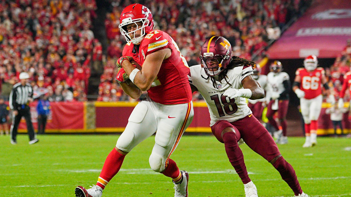Kansas City Chiefs tight end Travis Kelce (87) carries the ball defended by Washington Commanders safety Tyler Owens (18) during the second quarter of the game at GEHA Field at Arrowhead Stadium.