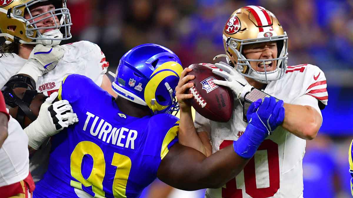 Los Angeles Rams defensive end Kobie Turner (91) sacks San Francisco 49ers quarterback Mac Jones (10) during overtime at SoFi Stadium.