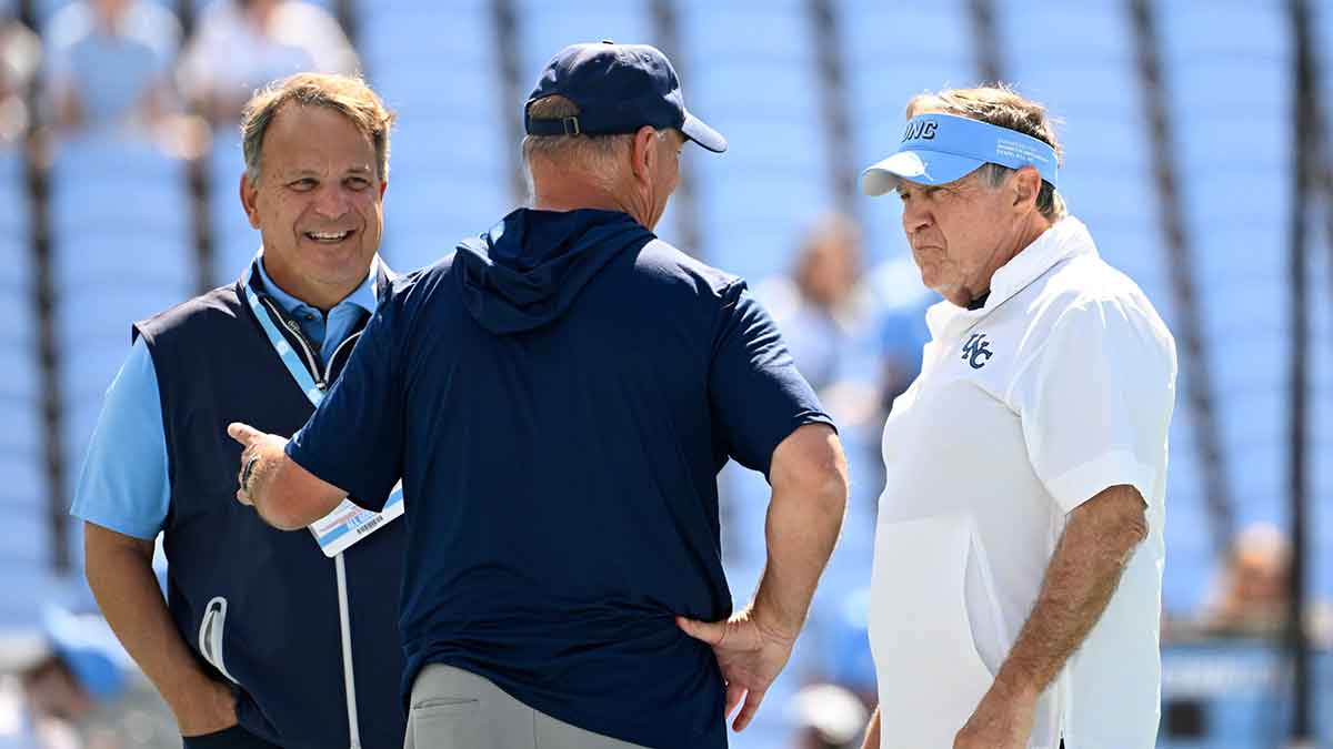 Richmond Spiders head coach Russ Huesman talks to North Carolina Tar Heels general manger Michael Lombardi and head coach Bill Belichick before the game at Kenan Stadium.