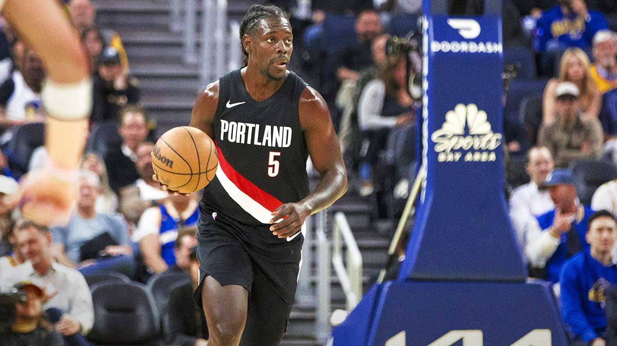 Blazers guard Jrue Holiday (5) takes the ball down the court against the Golden State Warriors during the second quarter at Chase Center with the Celtics logo in the background