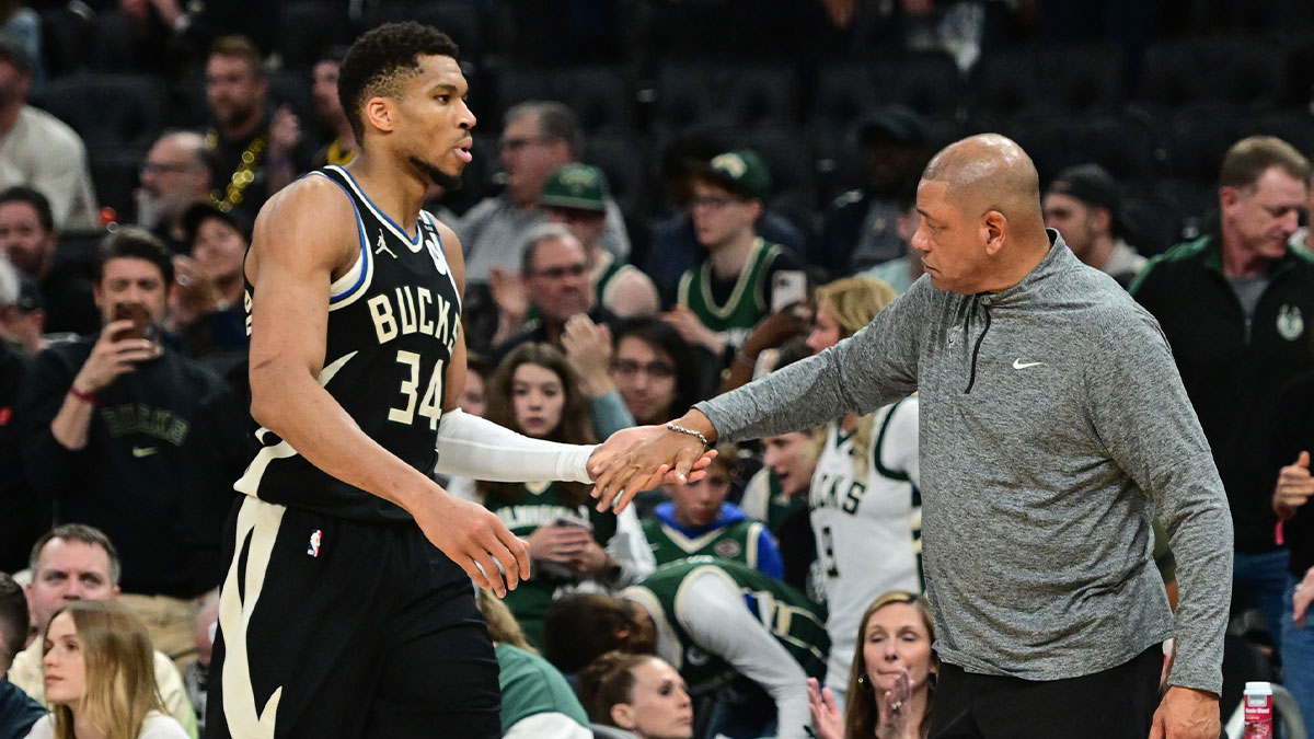 Bucks forward Giannis Antetokounmpo (34) exits the game in the fourth quarter as head coach Doc Rivers shakes his hand during game four against the Indiana Pacers of first round for the 2024 NBA Playoffs at Fiserv Forum with ESPN's Shams Charania in the background
