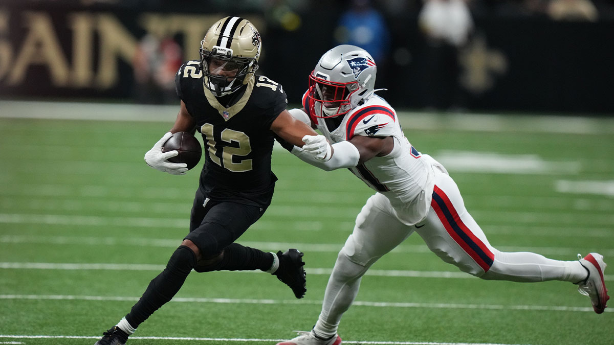New Orleans Saints wide receiver Chris Olave (12) runs for a gain past New England Patriots safety Craig Woodson (31) during the second quarter at Caesars Superdome.