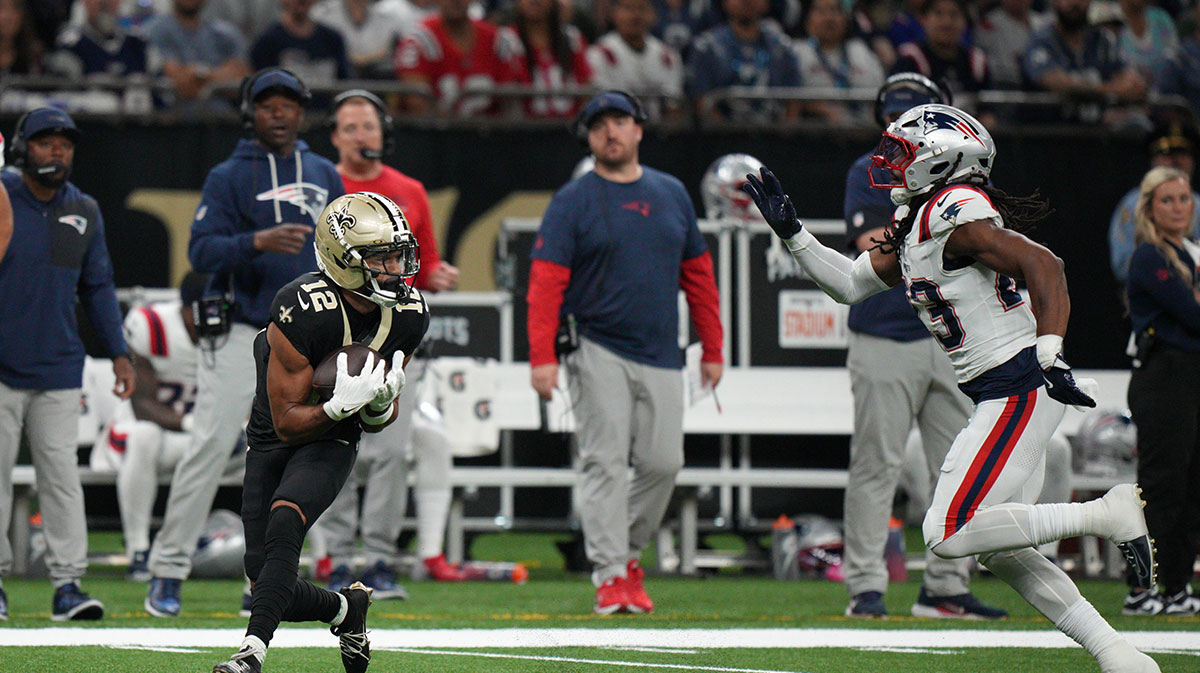 New Orleans Saints wide receiver Chris Olave (12) receives a kickoff under pressure from New England Patriots safety Kyle Dugger (23) during the first quarterat Caesars Superdome.