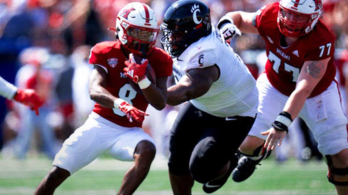 Miami Redhawks running back Kevin Davis (8) runs by Cincinnati Bearcats defensive tackle Dontay Corleone (2) in the first quarter of the College Football game.