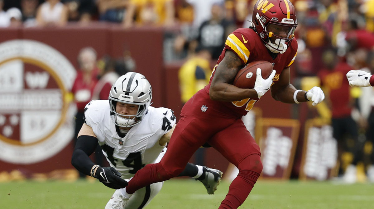Washington Commanders wide receiver Jaylin Lane (83) returns a punt past Las Vegas Raiders linebacker Tommy Eichenberg (44) at Northwest Stadium.