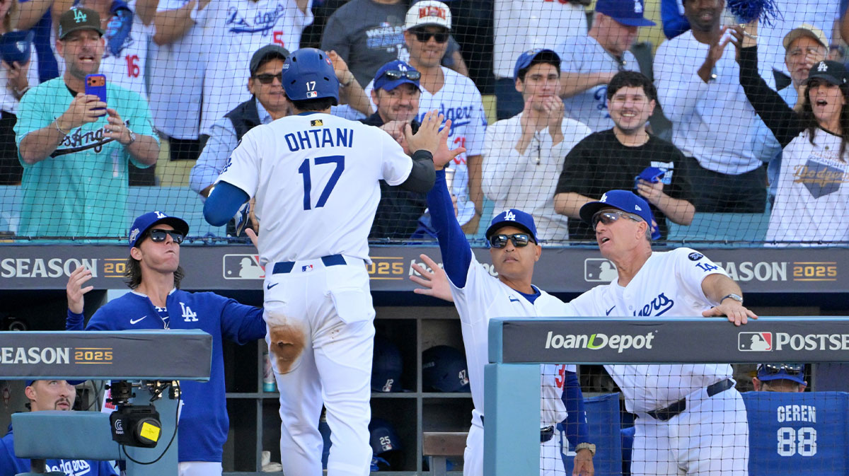 Los Angeles Dodgers two-way player Shohei Ohtani (17) celebrates with manager Dave Roberts (30) in the dugout after scoring against the Milwaukee Brewers in the first inning during game three of the NLCS round for the 2025 MLB playoffs at Dodger Stadium. Mandatory Credit: Jayne Kamin-Oncea-Imagn Images