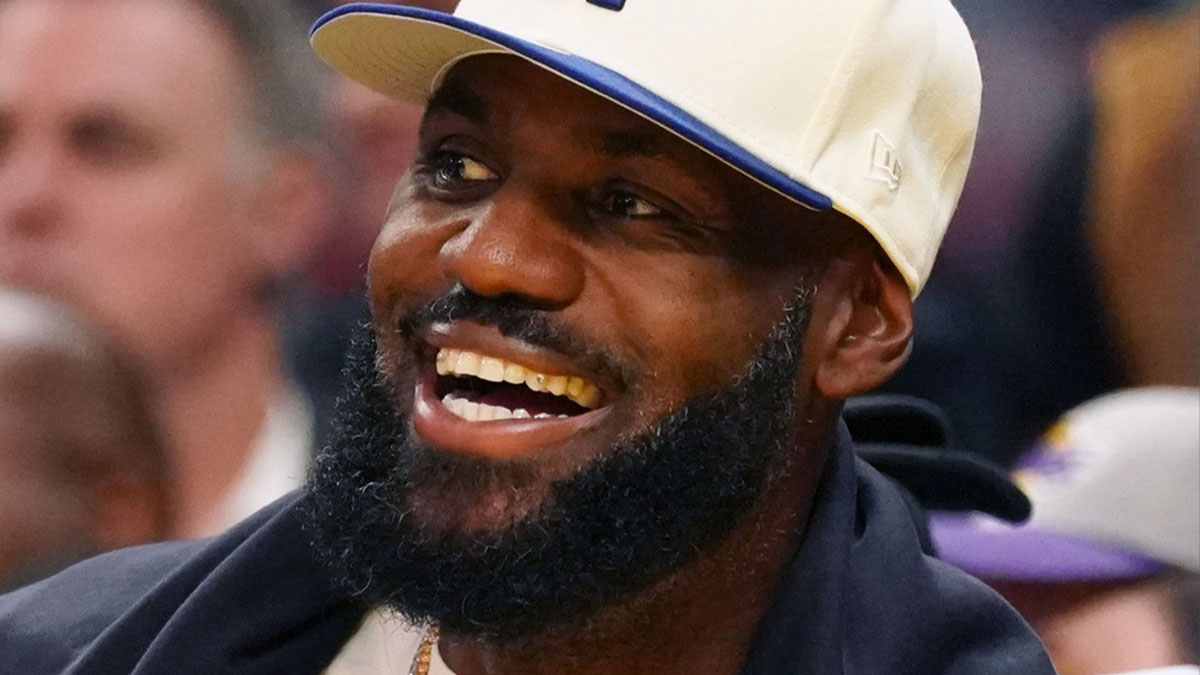 Oct 5, 2025; San Francisco, California, USA; Los Angeles Lakers forward LeBron James (23), wearing a Los Angeles Dodgers hat, smiles after watching his son, guard Bronny James (9), dunk a rebound against the Golden State Warriors in the third quarter at Chase Center. Mandatory Credit: David Gonzales-Imagn Images