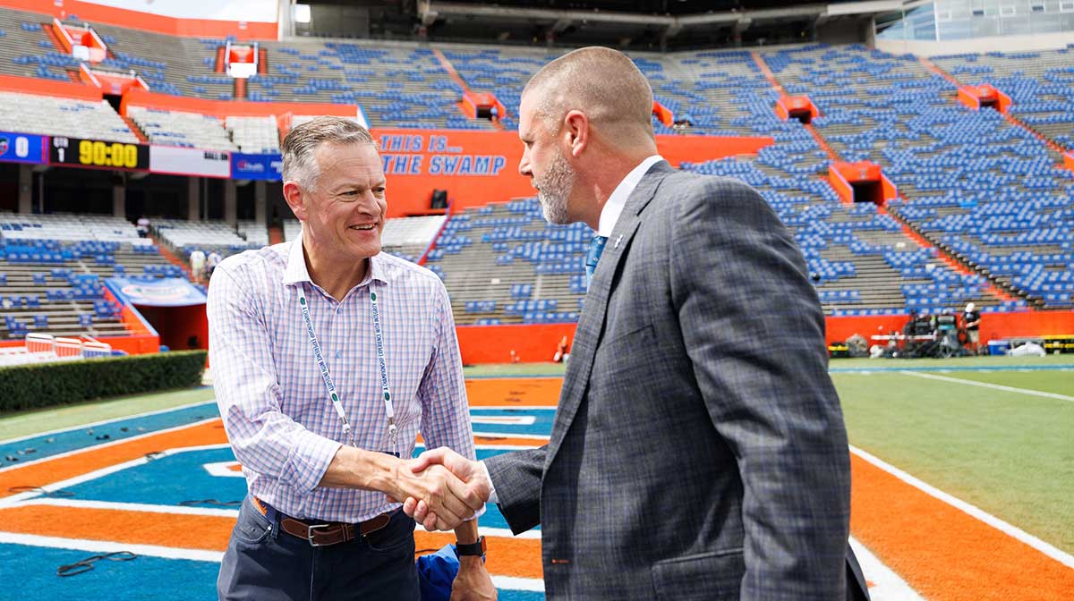 Florida Gators athletic director Scott Stricklin shakes hands with Florida Gators head coach Billy Napier before the game at Ben Hill Griffin Stadium.