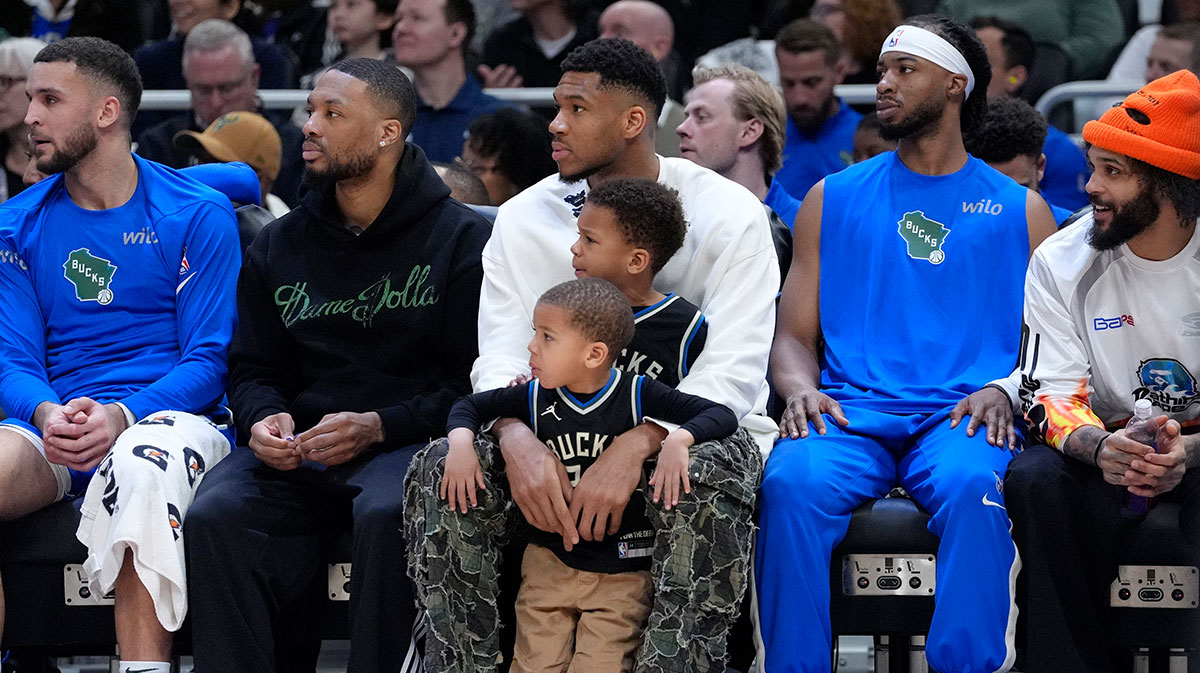 Milwaukee Bucks guard Damian Lillard (0) sits on the bench with Milwaukee Bucks forward Giannis Antetokounmpo (34) and his kids Liam and Maverick during the first half against the Detroit Pistons at American Family Field.