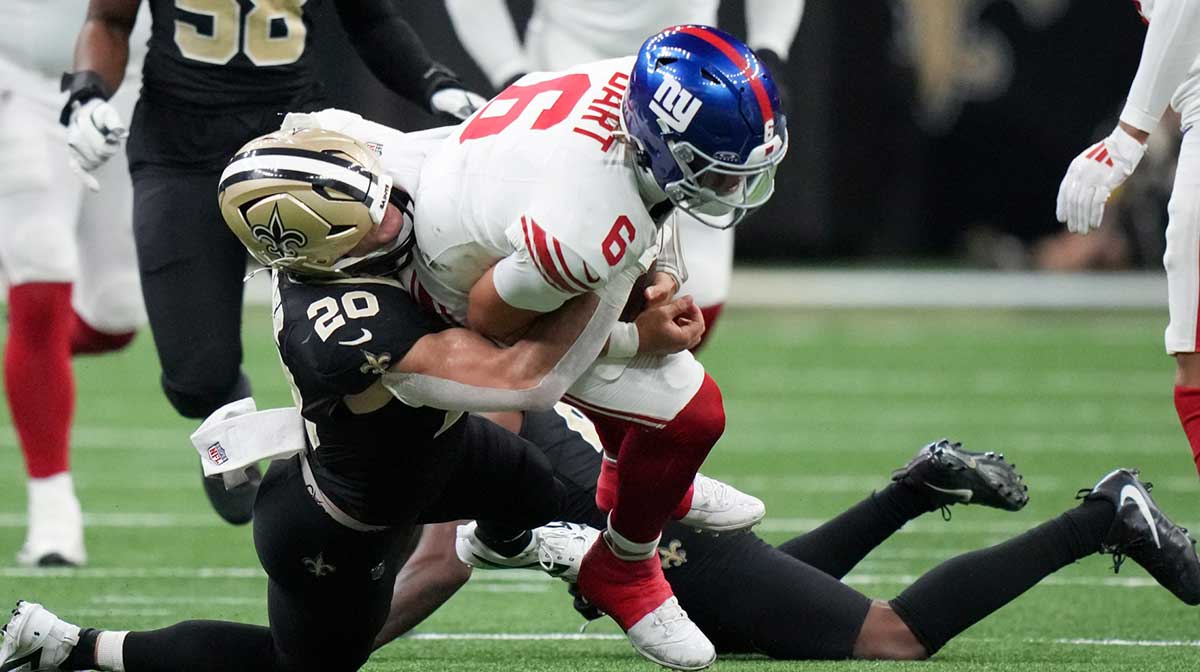 New Orleans Saints linebacker Pete Werner (20) tackles New York Giants quarterback Jaxson Dart (6) during the second quarter at Caesars Superdome.